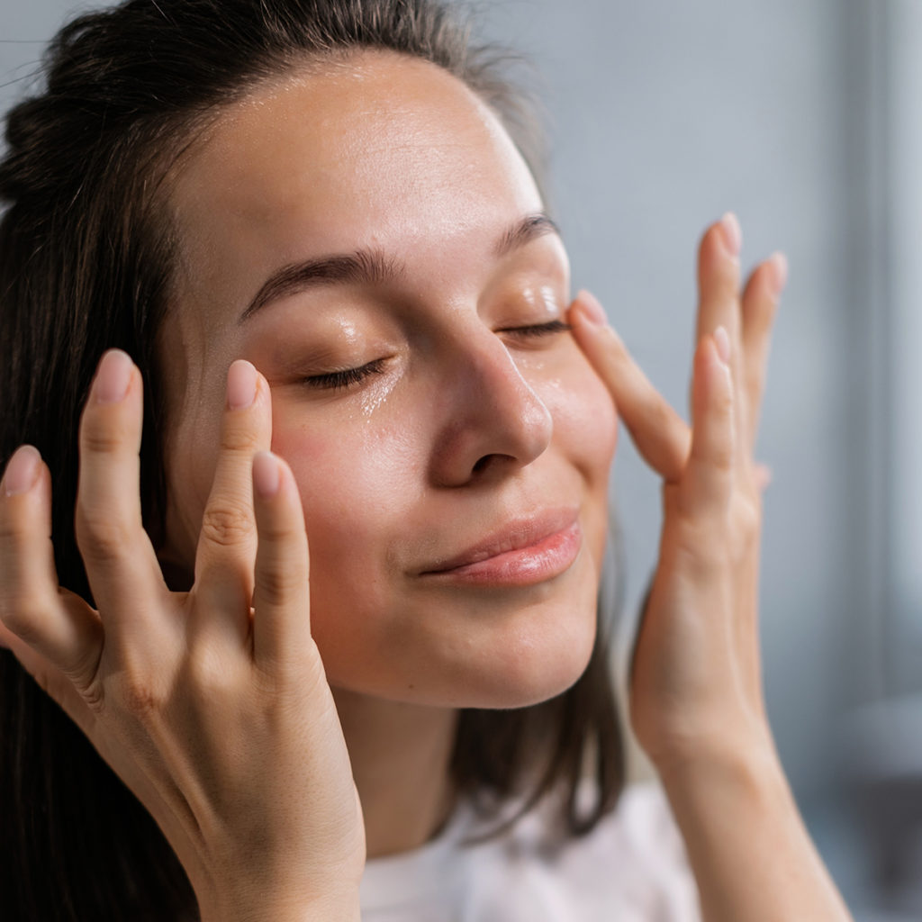 Woman applying under eye cream.